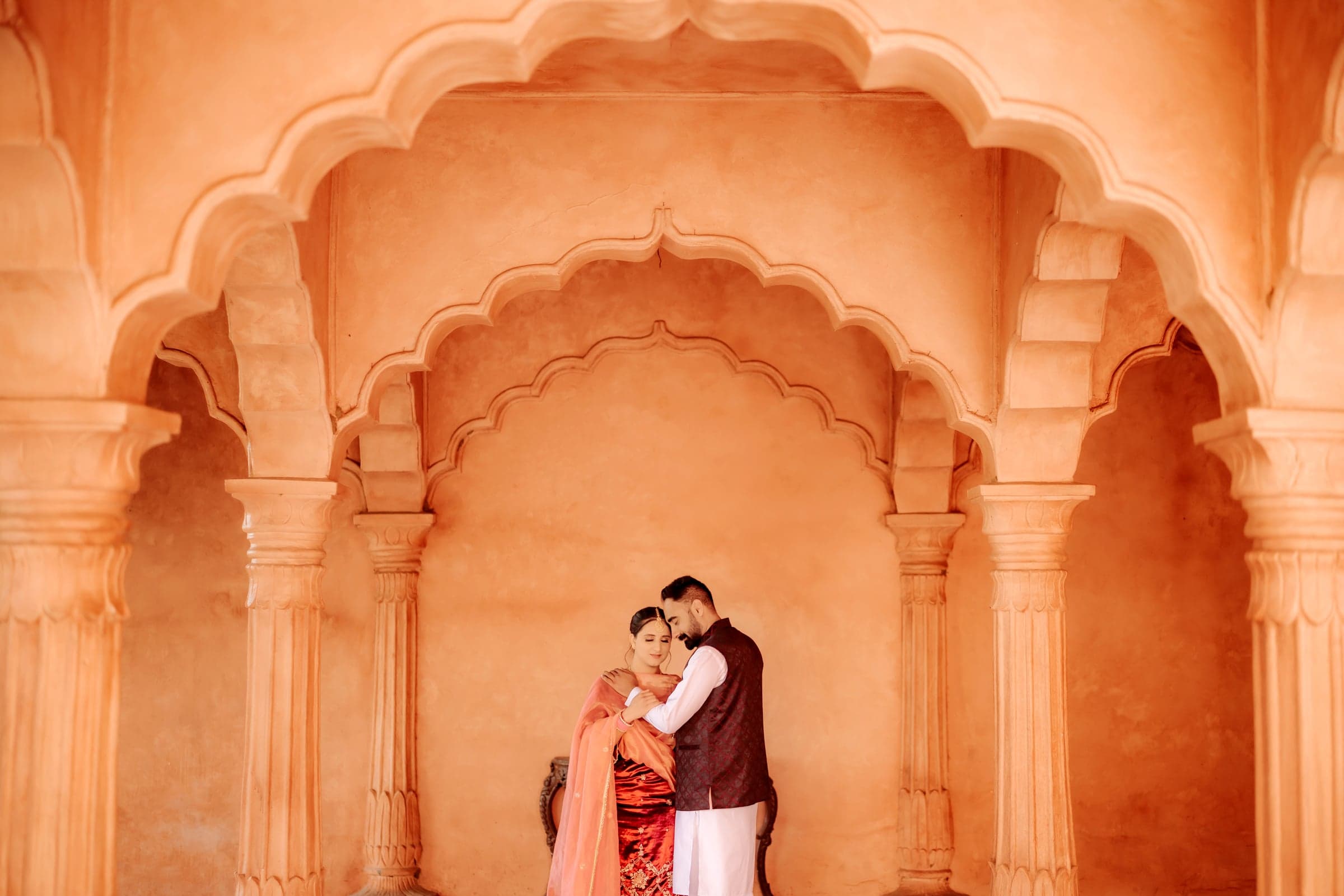 A couple embracing beneath sandstone Rajasthani archways