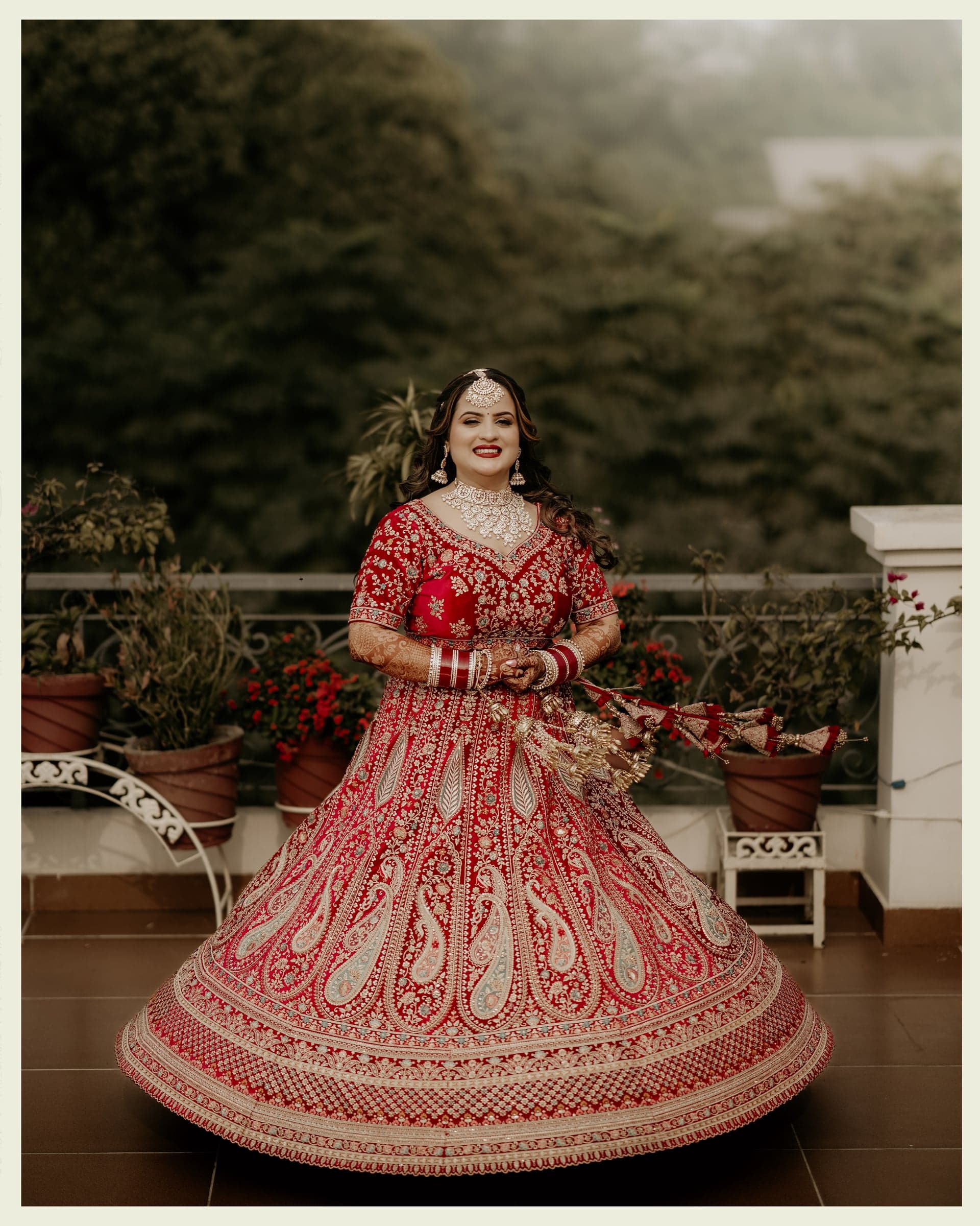 A bride mid-twirl in a red lehenga in front of a palm tree