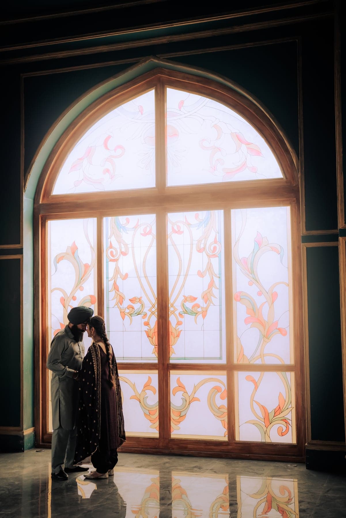 A couple walking together through a sunlit archway corridor