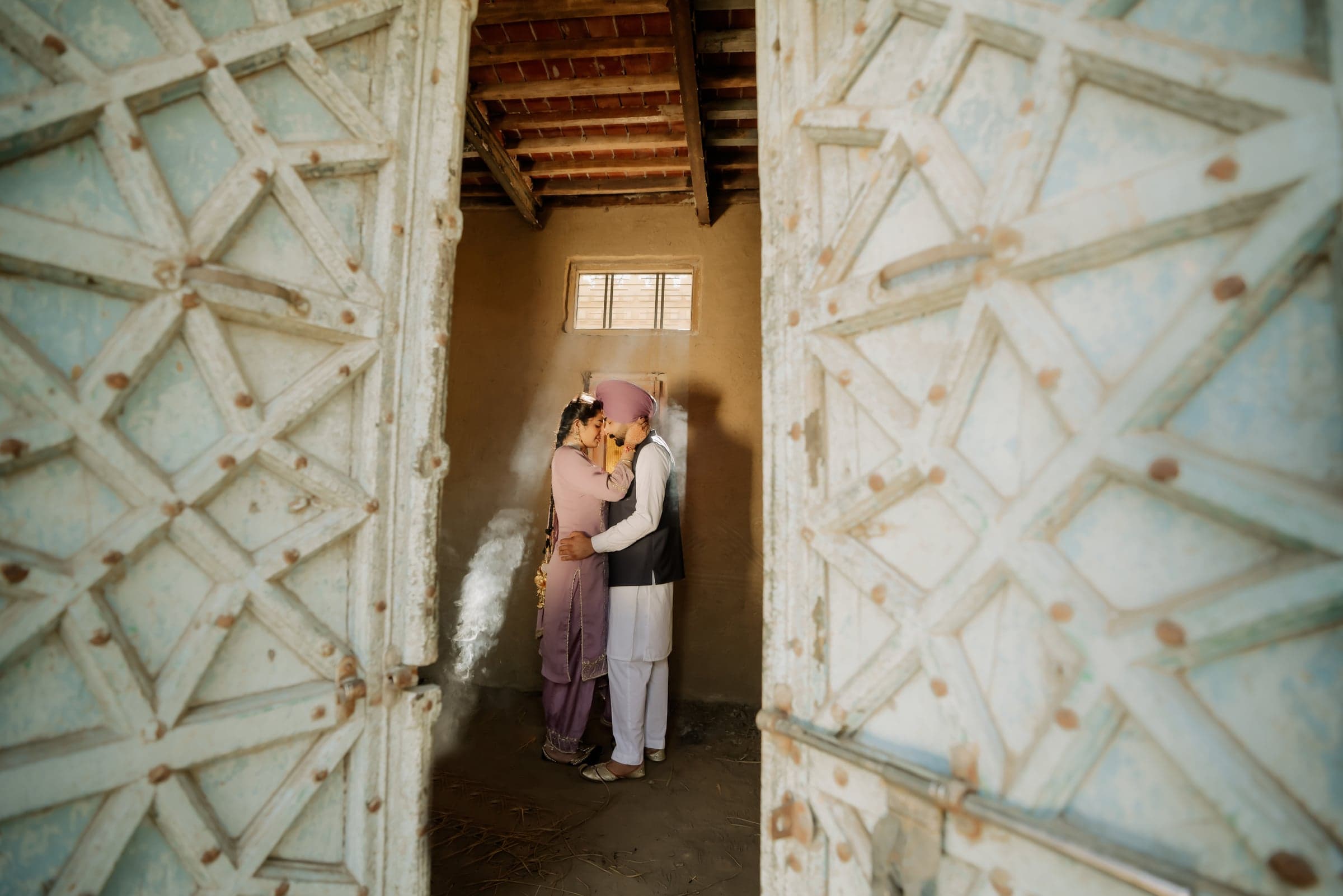 A couple sharing a quiet embrace in a sunlit doorway, incense smoke drifting between them
